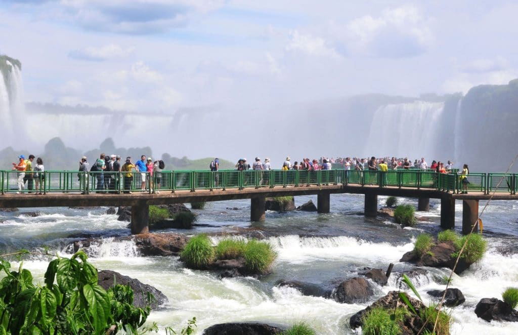 1. Imagem das Cataratas do Iguaçu, com quedas d’água e vegetação em frente a um céu azul.